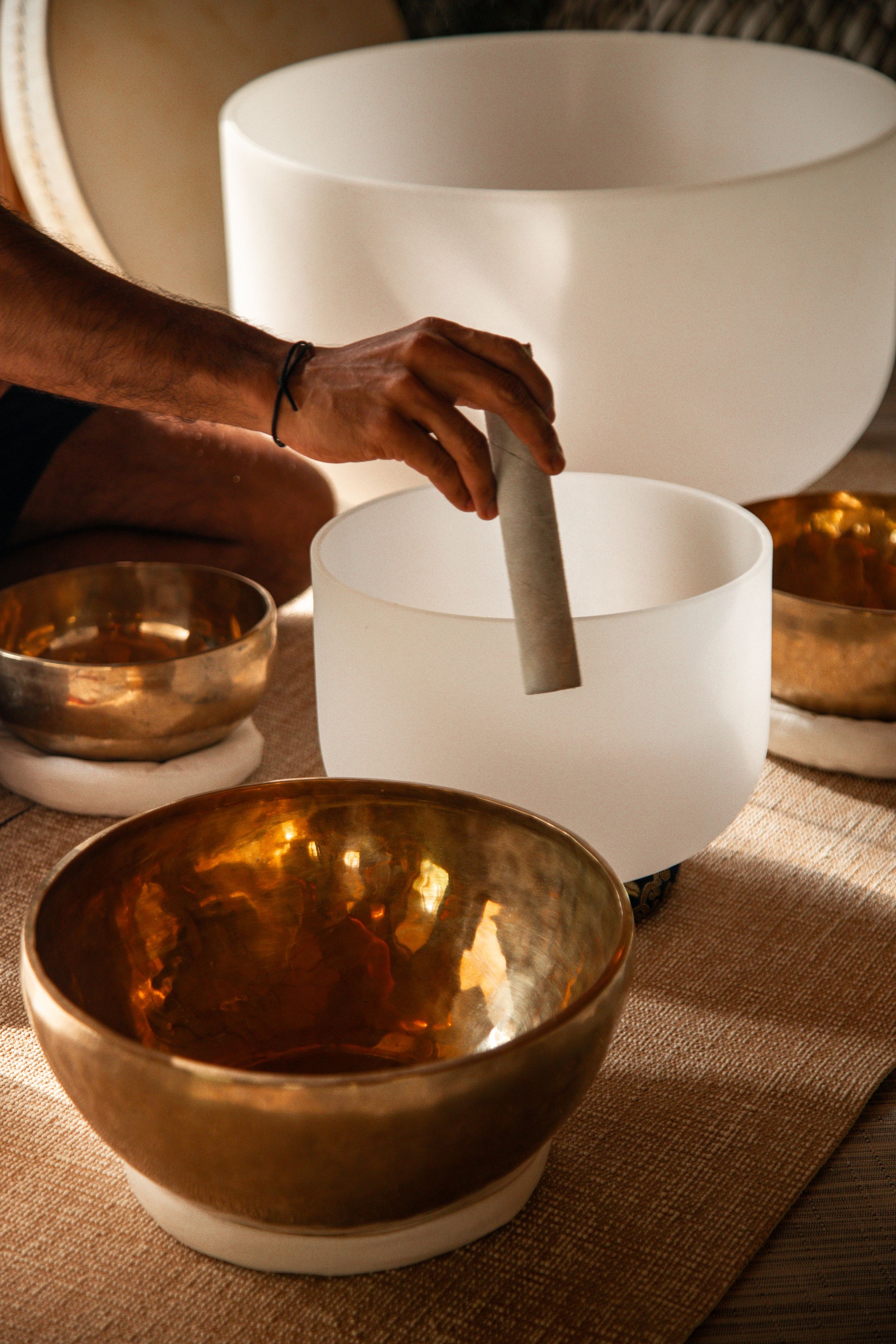 Spa therapist playing crystal singing bowls at wellness retreat for sound healing treatment meditation