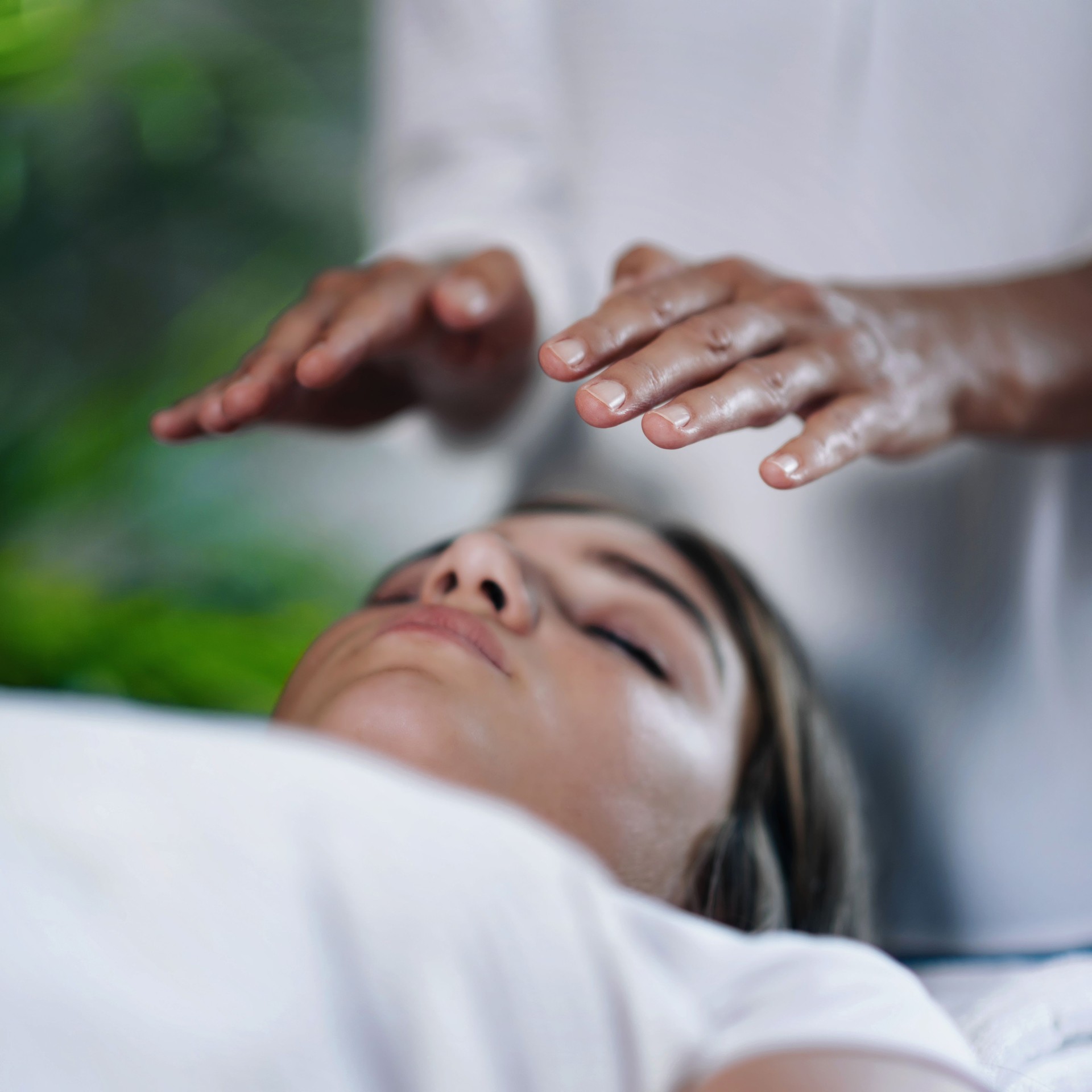 Midsection Of Therapist Giving Reiki Treatment To Teenage Girl On Face At Spa